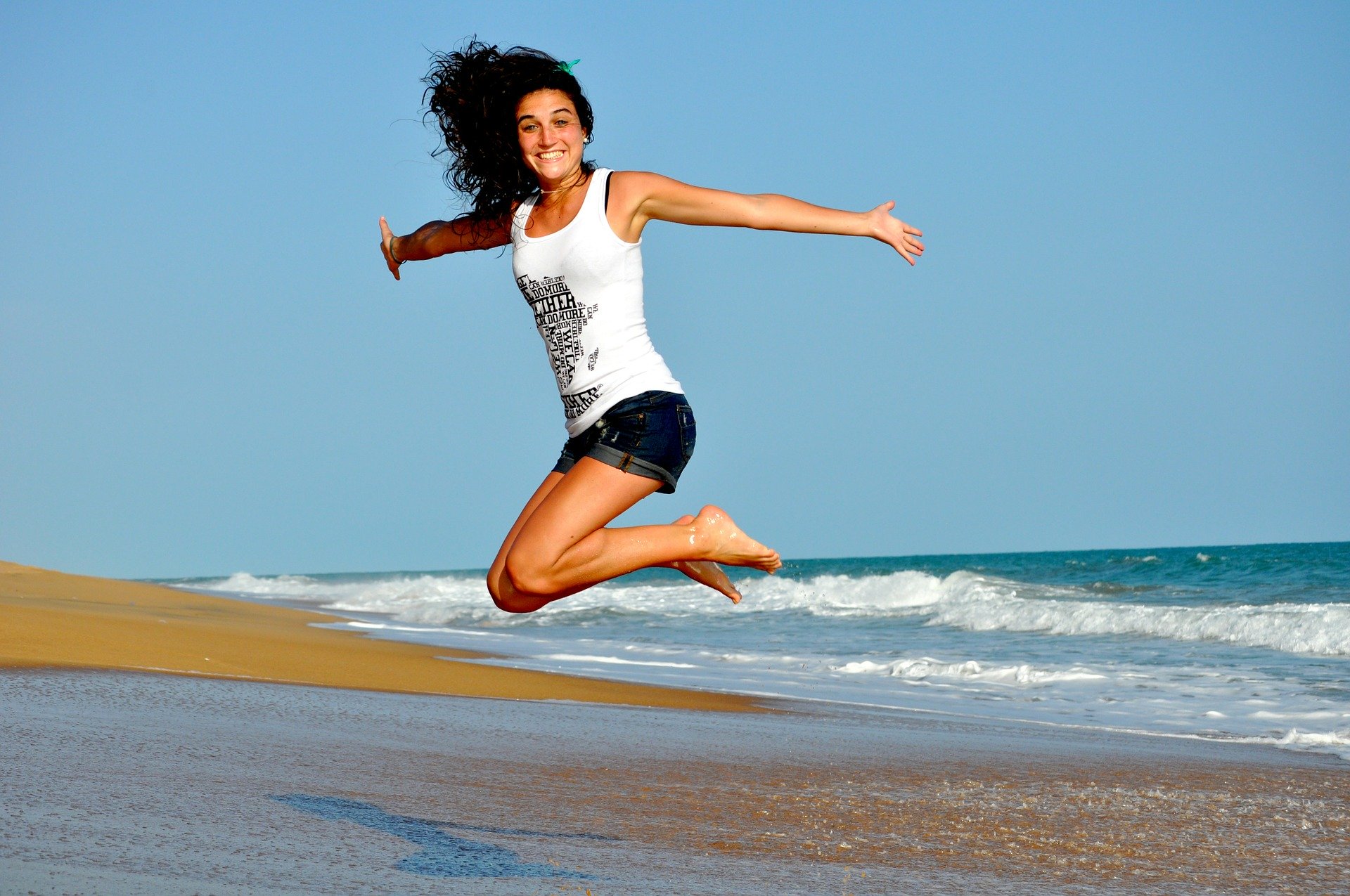 woman jumping at the beach, ocean in the background